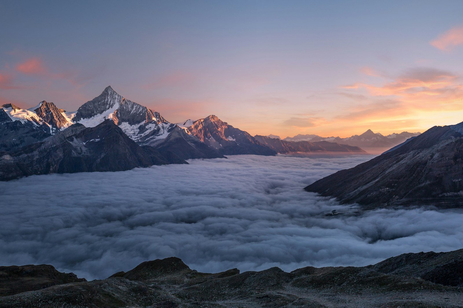 Agujas de granito iluminadas por la luz del atardecer con silueta de cordillera al fondo